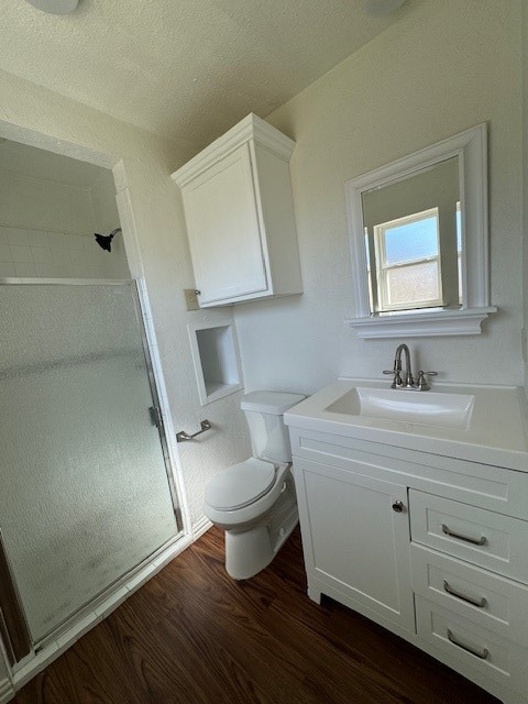 bathroom featuring vanity, toilet, hardwood / wood-style flooring, and an enclosed shower