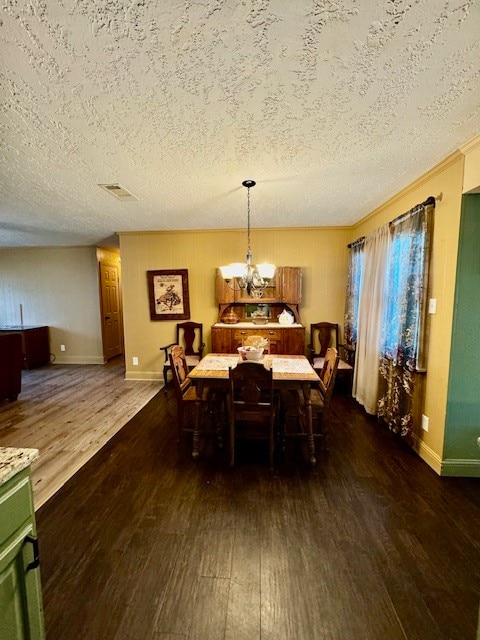 dining space featuring an inviting chandelier, a textured ceiling, and dark hardwood / wood-style flooring