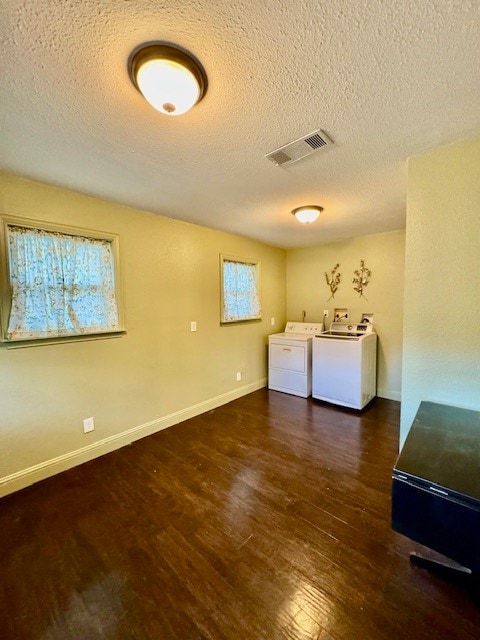 laundry area with dark wood-type flooring, washing machine and dryer, and a textured ceiling