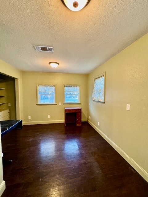 empty room featuring a textured ceiling and dark hardwood / wood-style flooring