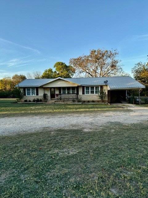 ranch-style home featuring covered porch, a front lawn, and a carport