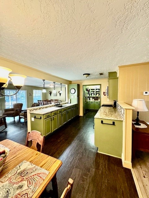 kitchen featuring sink, green cabinetry, a textured ceiling, kitchen peninsula, and dark wood-type flooring