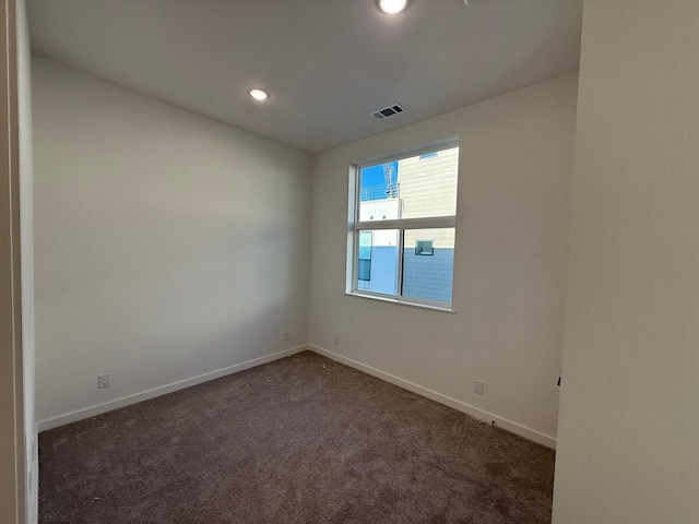 unfurnished room featuring dark carpet