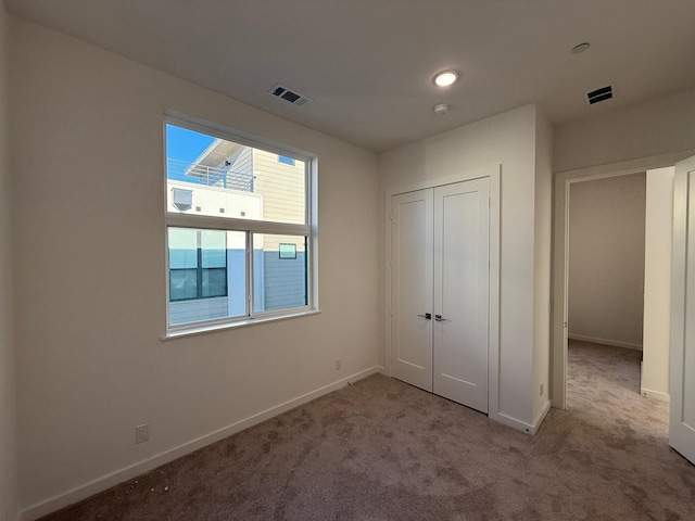 unfurnished bedroom with light colored carpet and a closet