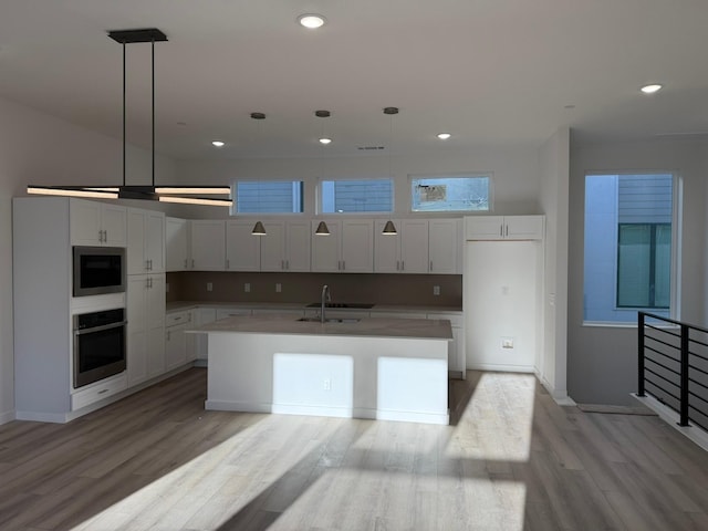 kitchen featuring pendant lighting, stainless steel oven, and white cabinetry