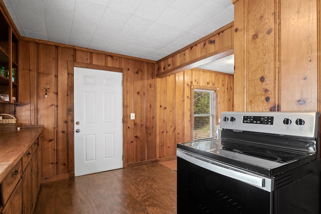 kitchen with dark wood-type flooring, electric range, and wooden walls