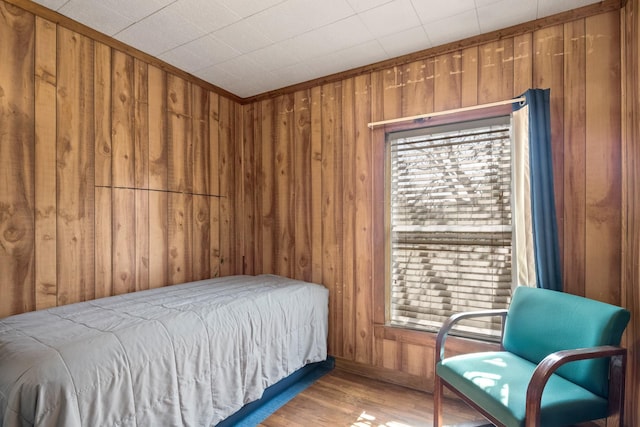 bedroom with multiple windows, wood walls, and wood finished floors