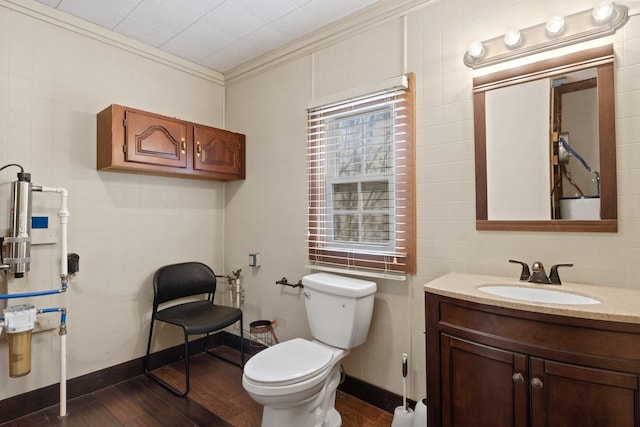 bathroom featuring toilet, ornamental molding, wood finished floors, and vanity