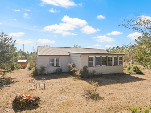 view of front of property with a fire pit, central AC, and metal roof