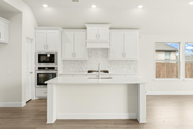 kitchen with built in microwave, white cabinets, sink, and stainless steel oven