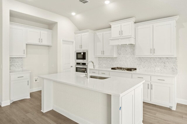 kitchen featuring lofted ceiling, sink, ceiling fan, white cabinets, and a center island with sink