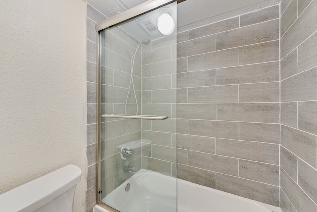 bathroom with toilet and combined bath / shower with glass door