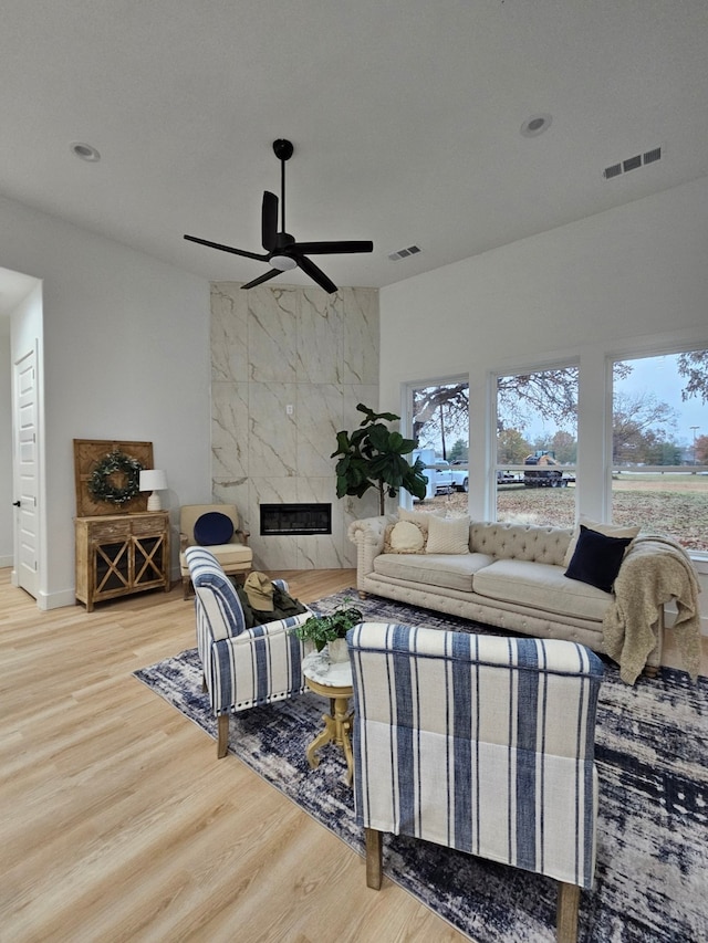 living room featuring ceiling fan, wood-type flooring, and a premium fireplace