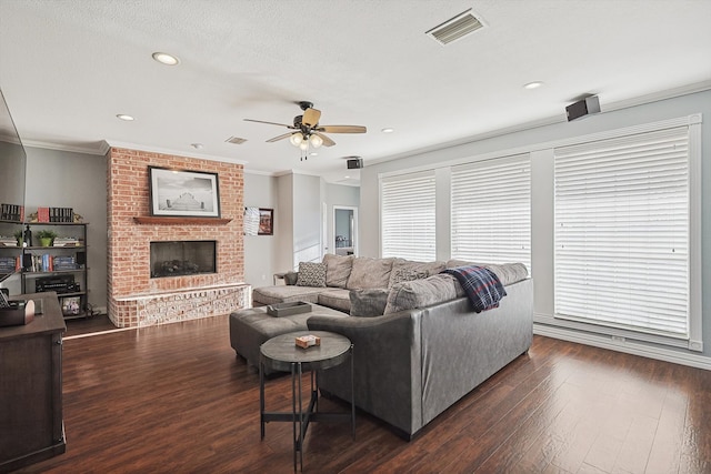 living room featuring ornamental molding, dark wood-type flooring, a fireplace, and ceiling fan