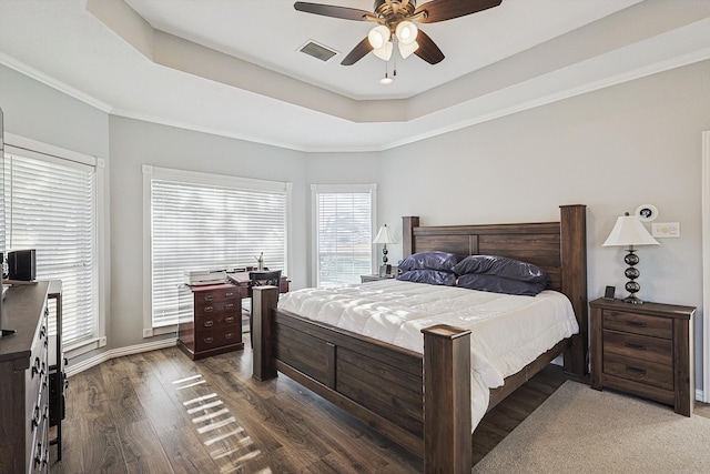 bedroom with ceiling fan, crown molding, a tray ceiling, and dark hardwood / wood-style floors