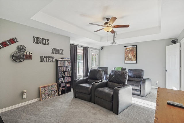 carpeted home theater featuring a tray ceiling and ceiling fan