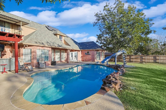 view of pool with a patio, a water slide, and a lawn