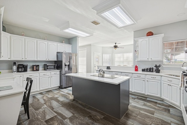 kitchen featuring a wealth of natural light, stainless steel fridge, a center island, and white cabinets