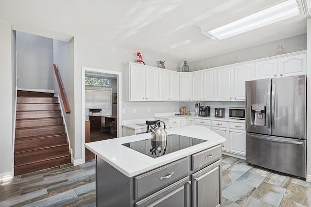 kitchen with stainless steel appliances, wood-type flooring, a center island, and white cabinets