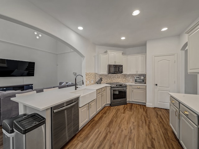 kitchen featuring kitchen peninsula, sink, white cabinets, and stainless steel appliances