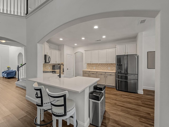 kitchen featuring dark wood-type flooring, sink, stainless steel refrigerator with ice dispenser, decorative backsplash, and white cabinetry