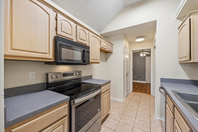 kitchen with light tile patterned floors, stainless steel appliances, light brown cabinetry, and vaulted ceiling