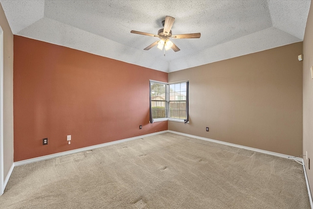 carpeted empty room featuring a raised ceiling, ceiling fan, a textured ceiling, and vaulted ceiling