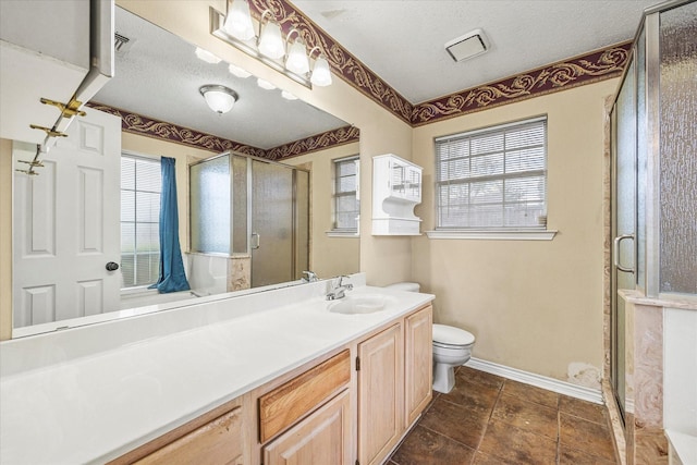 bathroom with a wealth of natural light, vanity, a textured ceiling, and toilet