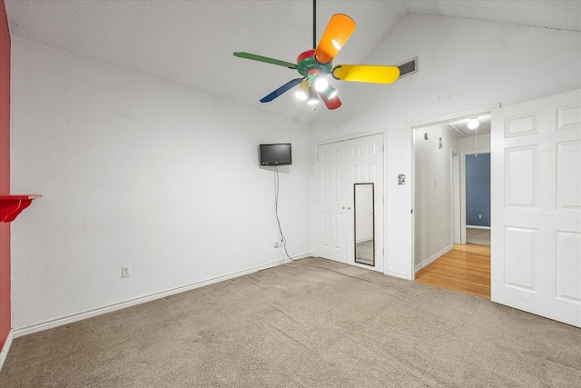 empty room with a textured ceiling, carpet floors, ceiling fan, and lofted ceiling