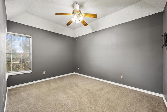 spare room featuring carpet, a textured ceiling, a raised ceiling, and ceiling fan