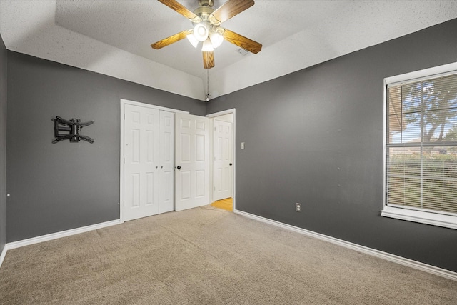 unfurnished bedroom with ceiling fan, a raised ceiling, lofted ceiling, light carpet, and a closet