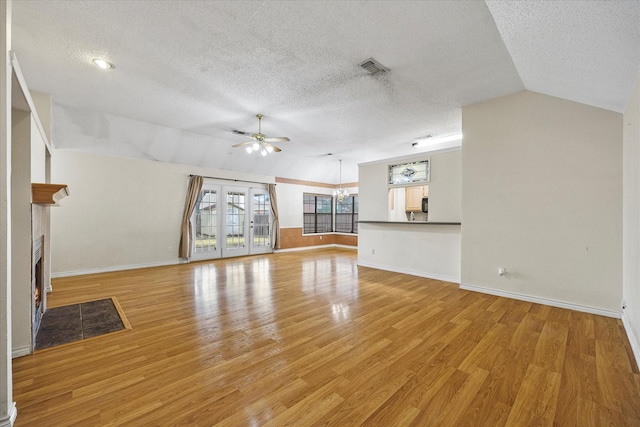 unfurnished living room with ceiling fan, lofted ceiling, a textured ceiling, and light hardwood / wood-style flooring