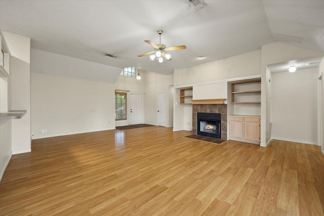 unfurnished living room featuring a textured ceiling, ceiling fan, light wood-type flooring, and a fireplace