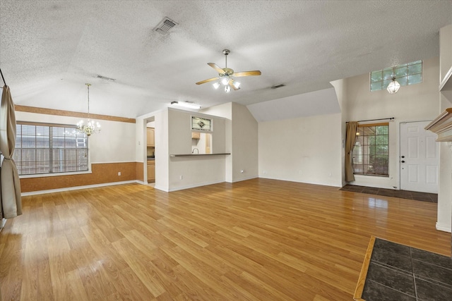 unfurnished living room featuring hardwood / wood-style floors, ceiling fan with notable chandelier, a healthy amount of sunlight, and vaulted ceiling