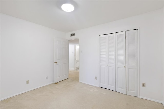 unfurnished bedroom featuring a closet and light colored carpet