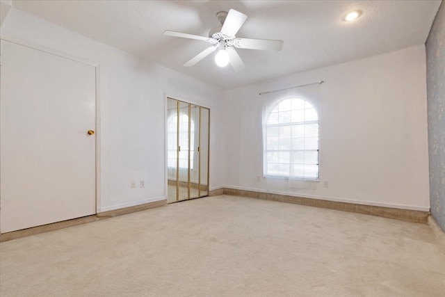 spare room featuring light colored carpet and ceiling fan