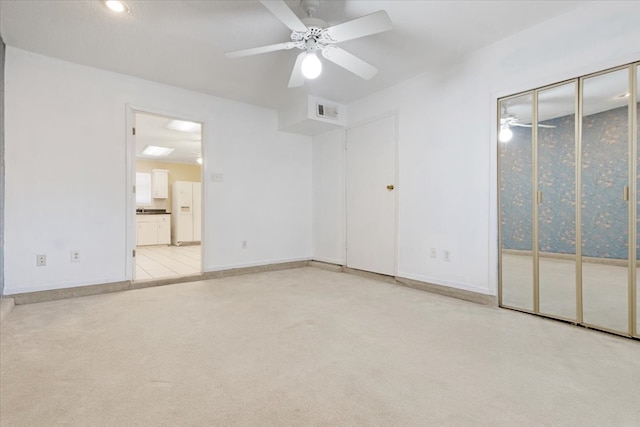 unfurnished bedroom featuring connected bathroom, access to outside, light carpet, white refrigerator with ice dispenser, and ceiling fan