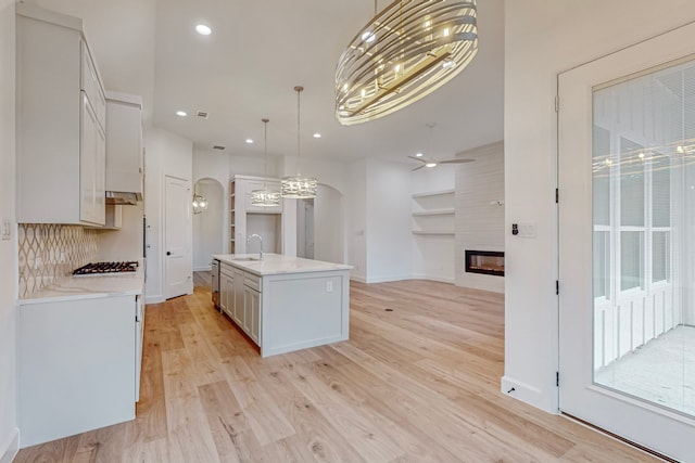 kitchen with a center island with sink, sink, white cabinets, and light hardwood / wood-style flooring