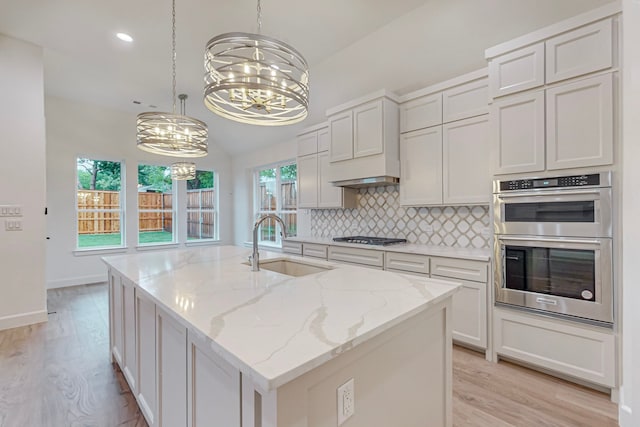 kitchen with white cabinetry, sink, an island with sink, and hanging light fixtures