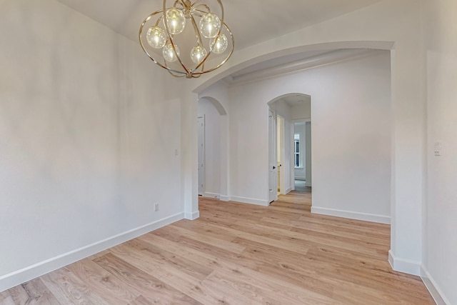 empty room with a chandelier and light hardwood / wood-style floors