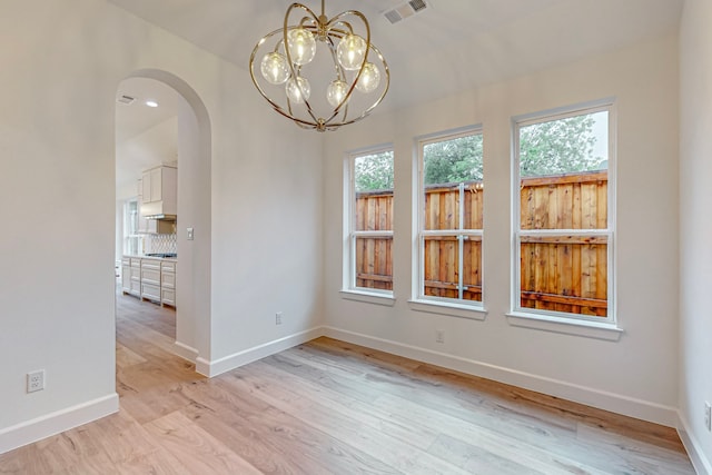 unfurnished dining area with light hardwood / wood-style flooring and a notable chandelier