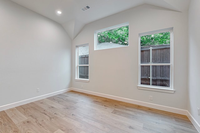 spare room with light hardwood / wood-style floors, vaulted ceiling, and a wealth of natural light