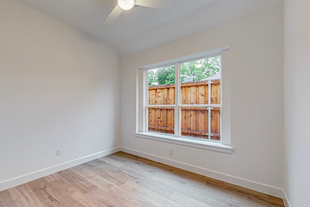 spare room featuring lofted ceiling, light wood-type flooring, and ceiling fan