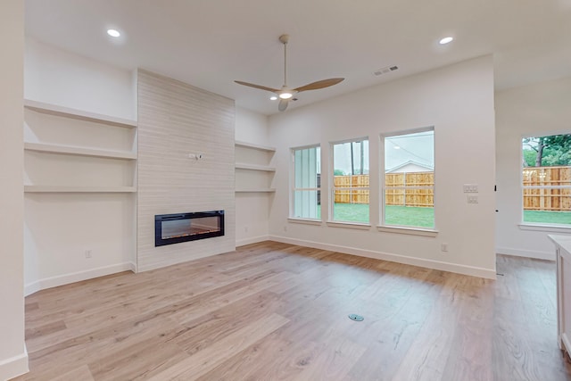 unfurnished living room with a wealth of natural light, a fireplace, light hardwood / wood-style floors, and ceiling fan