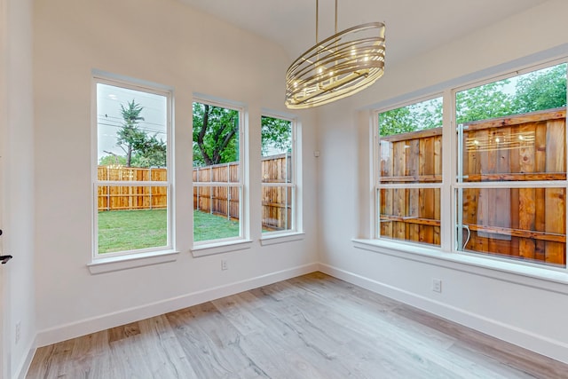 unfurnished dining area featuring a notable chandelier and light wood-type flooring