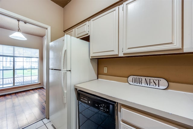 kitchen with white cabinetry, decorative light fixtures, white refrigerator, black dishwasher, and light hardwood / wood-style floors