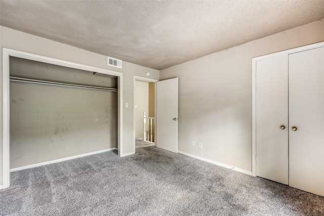 unfurnished bedroom featuring multiple closets, a textured ceiling, and carpet flooring