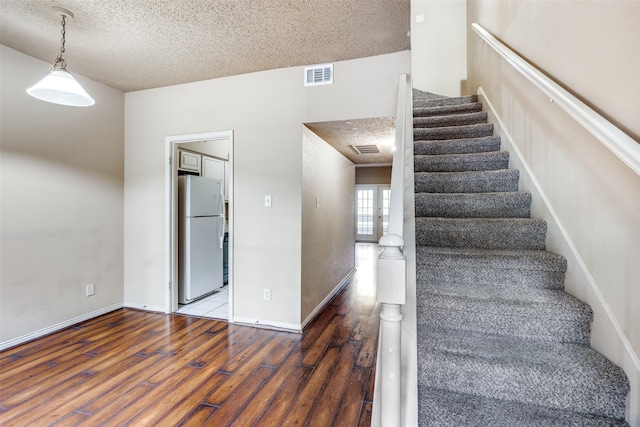 stairway with wood-type flooring and a textured ceiling