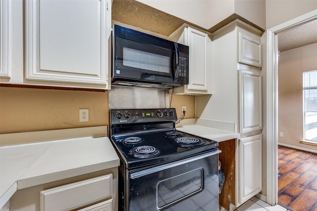 kitchen with white cabinets, light wood-type flooring, and black appliances