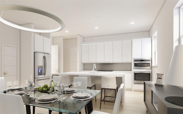 kitchen with fridge with ice dispenser, white cabinetry, stainless steel double oven, backsplash, and light wood-type flooring